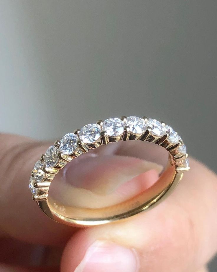 a person holding a gold ring with white stones on the inside and outside of it