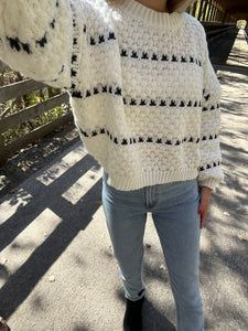 a woman standing next to a brown horse wearing a white sweater and black booties