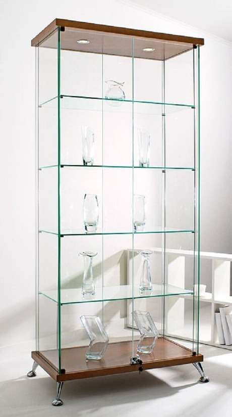 an empty glass case with several glasses in it on a wooden shelf next to a white wall