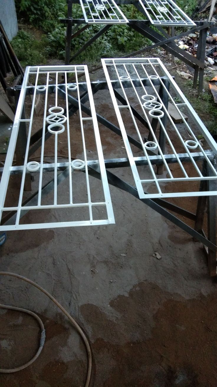 two metal tables sitting on top of a dirt ground