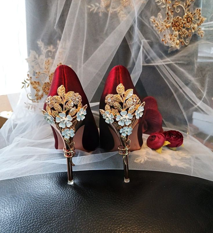 Elevate your formal event look with these luxurious Burgundy Wine Red Satin Bridal Shoes featuring a beautifully carved floral heel design. Perfect for a Gothic-inspired wedding, these elegant heels are ideal for brides or bridesmaids looking to make a statement. The rich burgundy color adds a touch of sophistication, while the intricate floral detail on the heels adds a romantic and unique twist to your ensemble. Step into style and comfort with these exquisite pumps that are sure to turn heads Glamorous Gold Wedding Shoes For Banquet, Gold Closed-toe Wedding Shoes For Banquet, Elegant Red Open Toe Wedding Shoes, Gold Pointed Toe Wedding Shoes For Banquet, Elegant Gold Wedding Shoes For Banquet, Elegant Gold Heels For Banquet, Glamorous Red Wedding Shoes For Formal Occasions, Red Glamorous Wedding Shoes, Elegant Open Toe Bridal Party Accessories