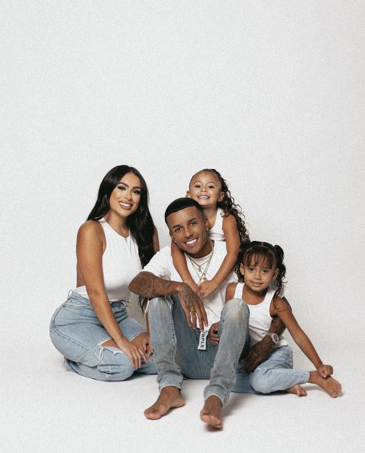 a family sitting on the floor posing for a photo in front of a white background