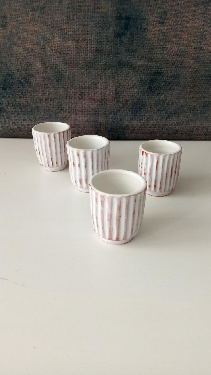 three small white cups sitting on top of a table next to each other and one is empty