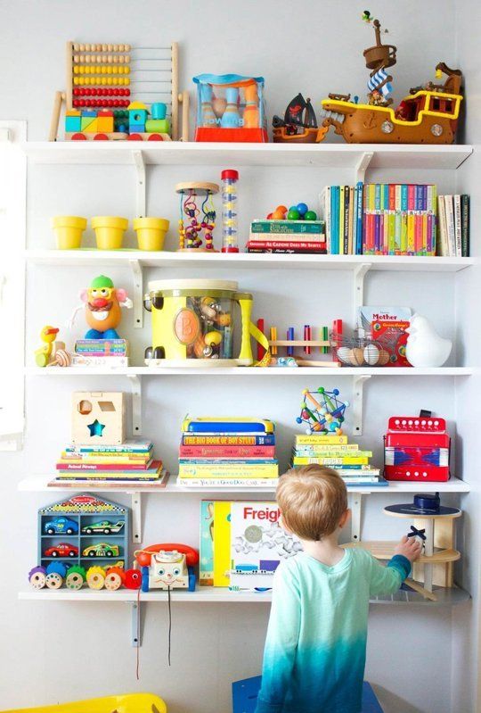 a little boy sitting at a desk in front of a book shelf filled with books