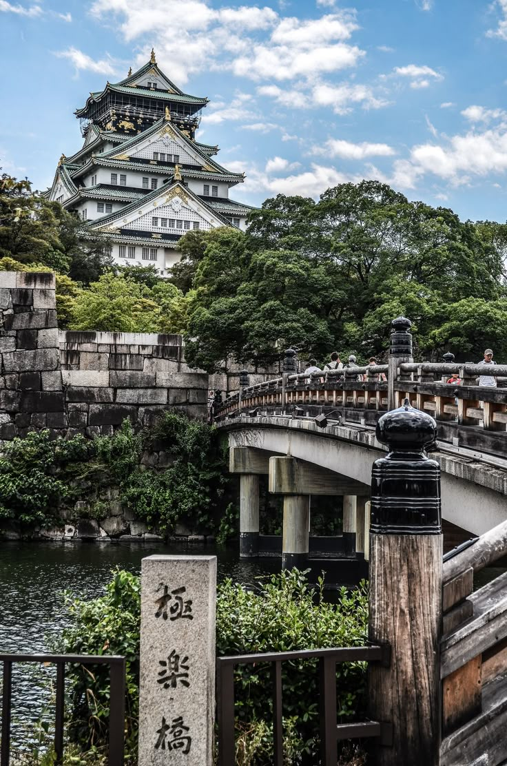 a bridge that is over some water with a building in the background and people walking on it