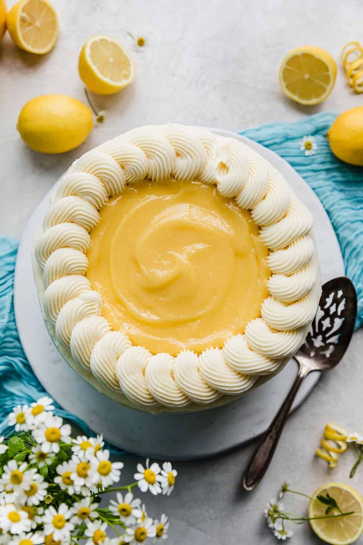 a lemon custard pie on a white plate with flowers and lemons around it