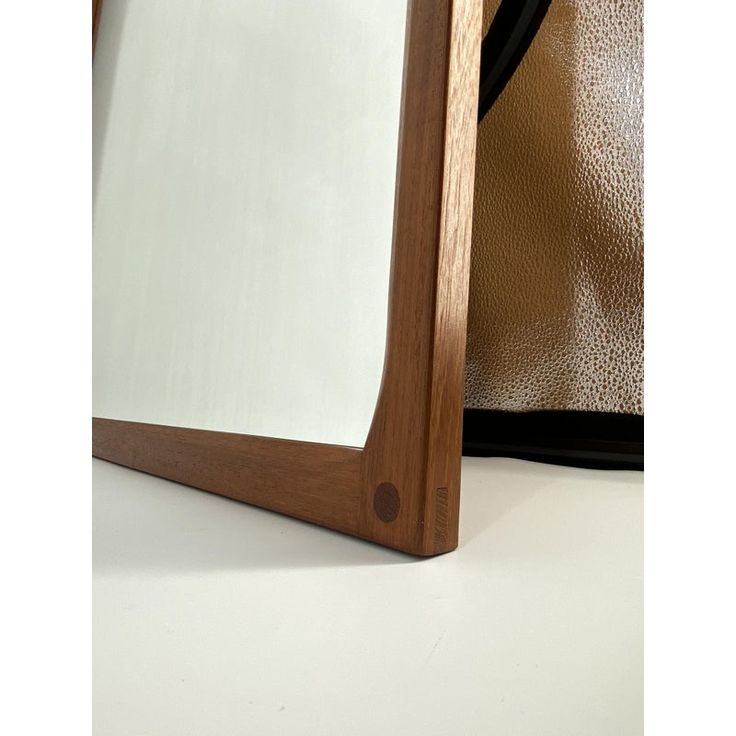 a mirror sitting on top of a white counter next to a brown leather bag and purse