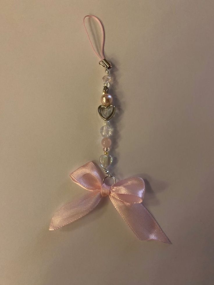 a key chain with a pink bow and beads hanging from it's side on a white surface