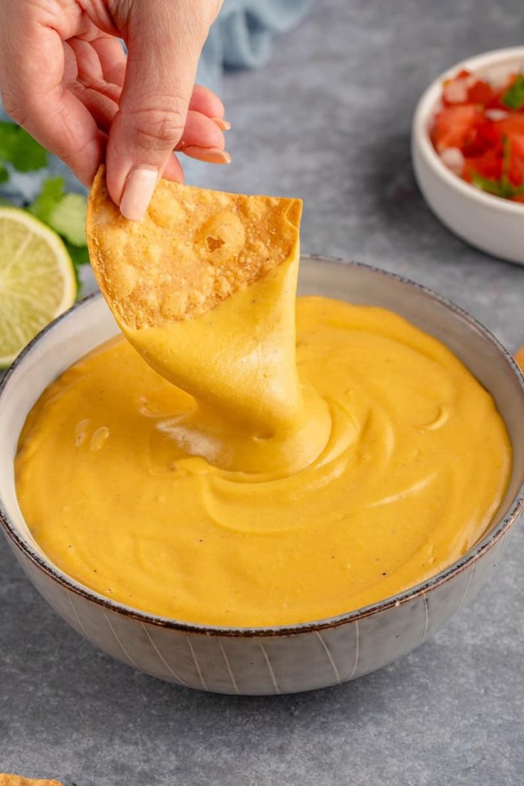 a tortilla chip being dipped into a bowl of salsa