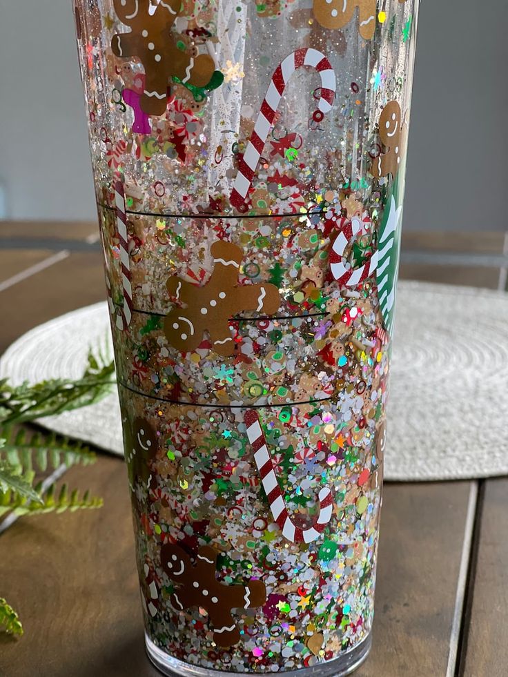 a glass filled with lots of different types of confetti on top of a wooden table