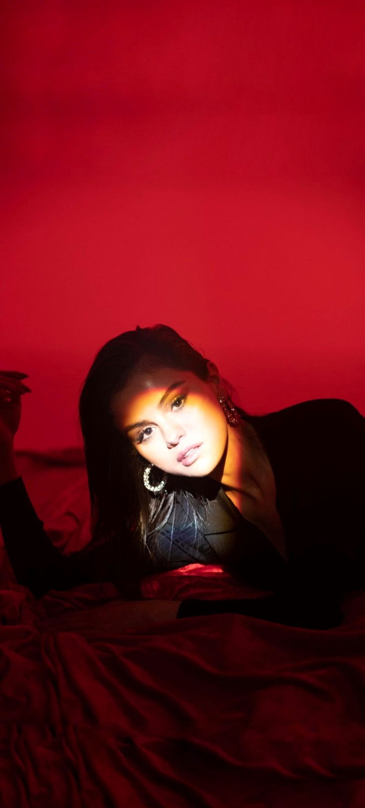 a woman laying on top of a bed under a red light