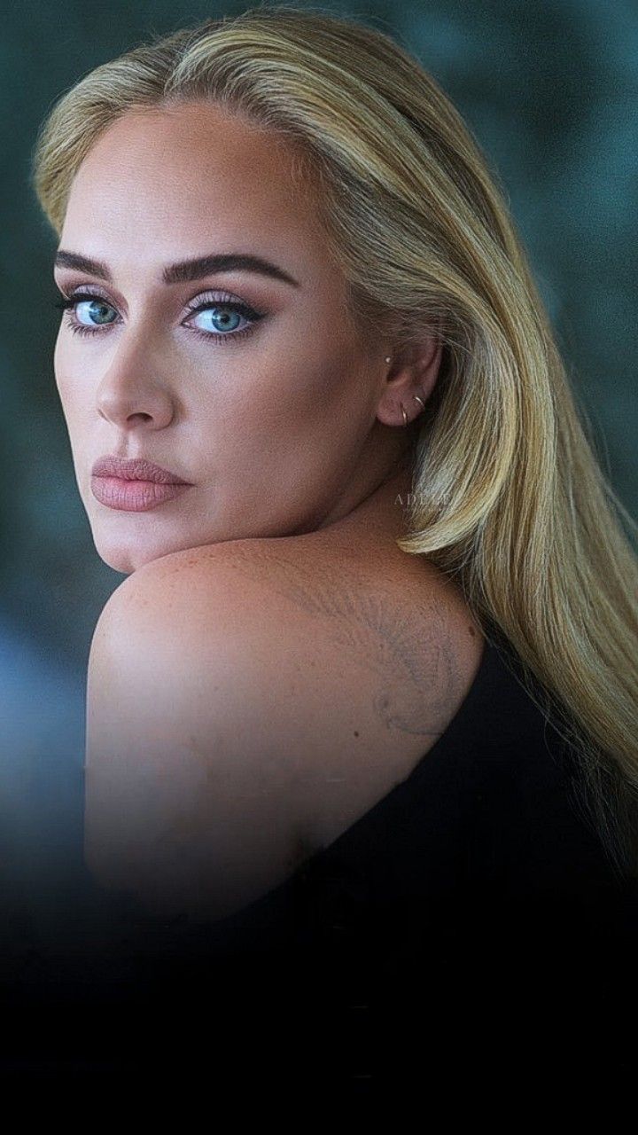 a woman with long blonde hair and blue eyes looking off to the side in front of a dark background