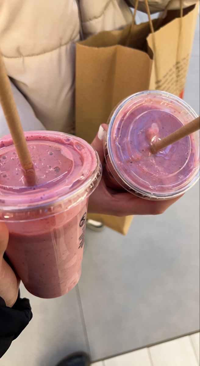 two people holding up drinks with straws in their hands, one is pink and the other is blue