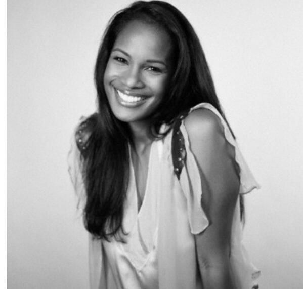 a black and white photo of a woman smiling for the camera with her hands on her hips