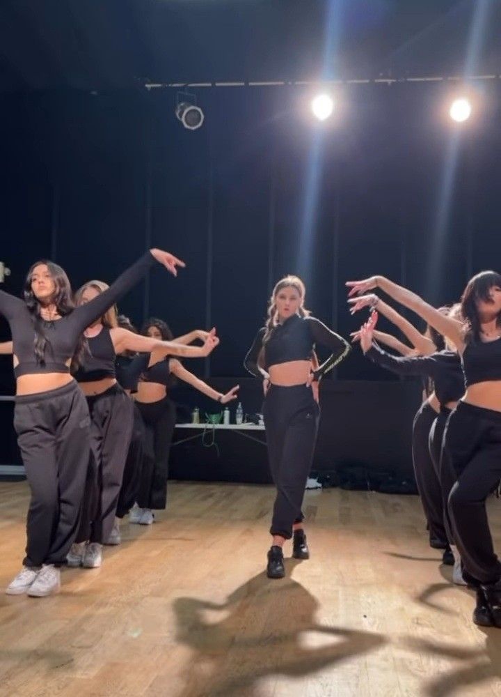 a group of young women dancing on top of a wooden floor with their arms in the air