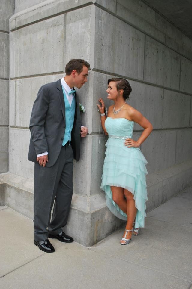 a man and woman standing next to each other in front of a stone wall,