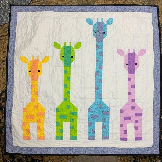 three giraffes on a white quilted wall hanging