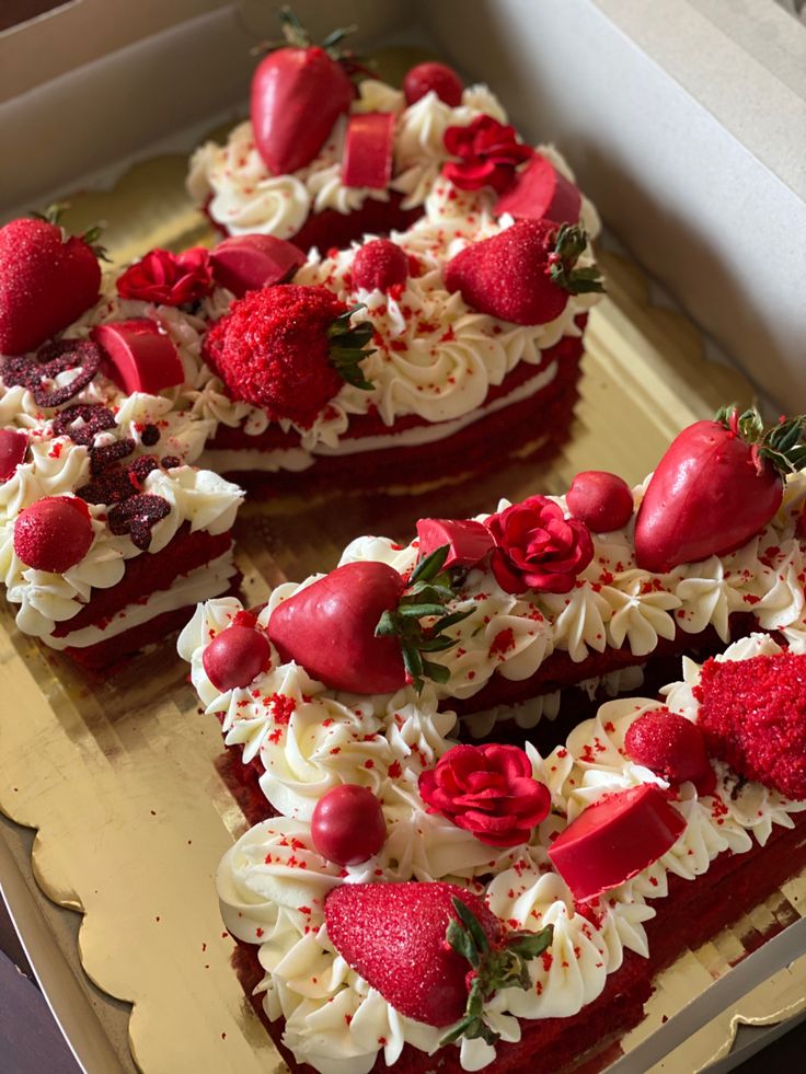 two heart shaped cakes with strawberries and cream frosting in a cardboard box on top of a table