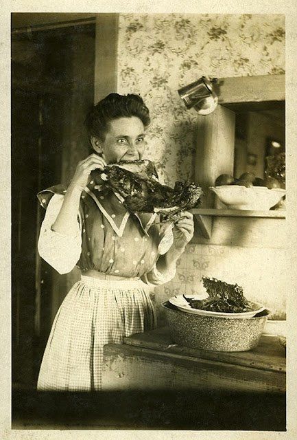 an old black and white photo of a woman holding food in her hands while looking at the camera