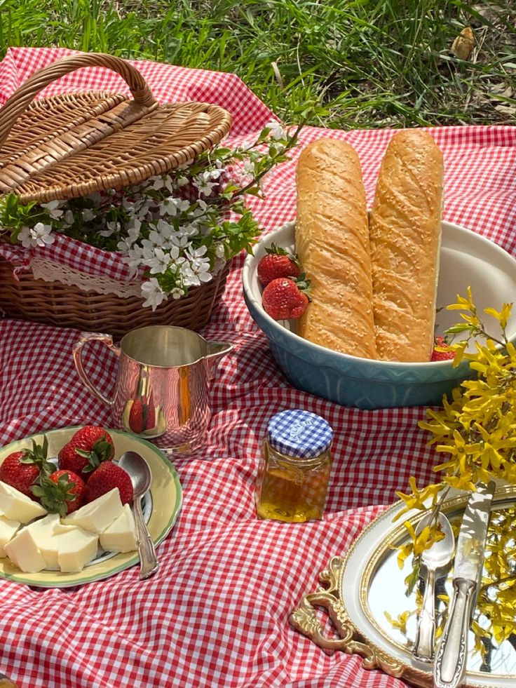 a picnic table with bread, cheese and strawberries