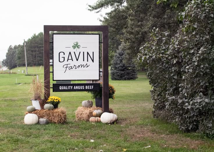 a sign for gavin farms with hay bales and pumpkins in the grass