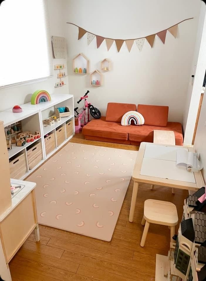 a small child's playroom with a couch, table and toy storage bins