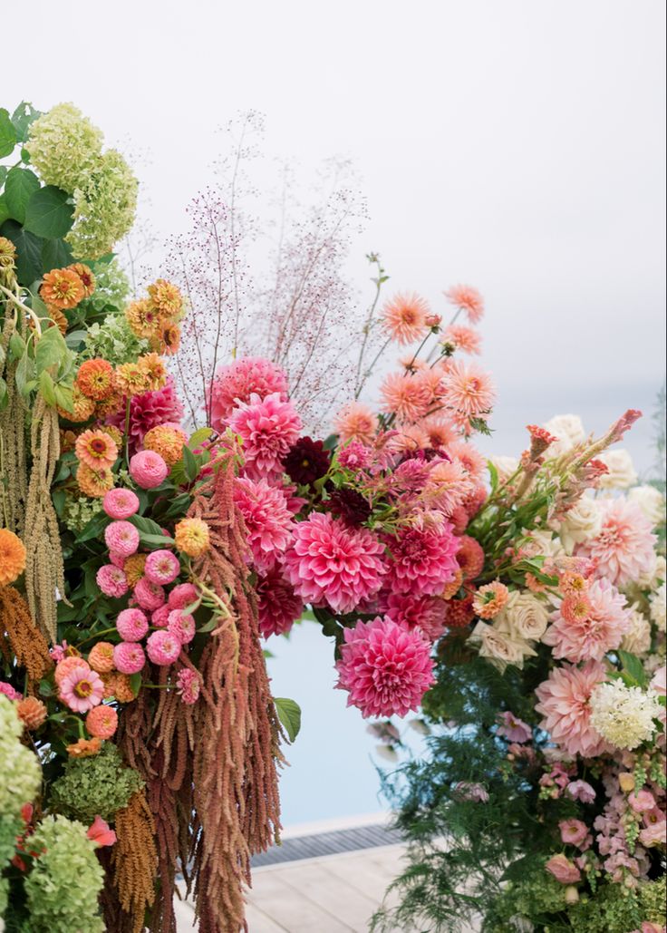 an arrangement of colorful flowers on display at a flower shop near the water's edge