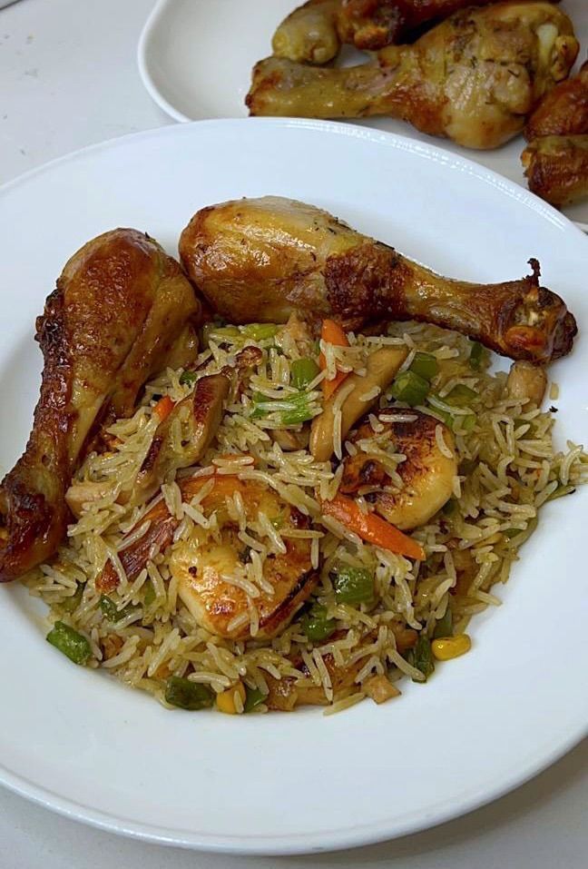 two white plates filled with food on top of a table next to chicken wings and rice