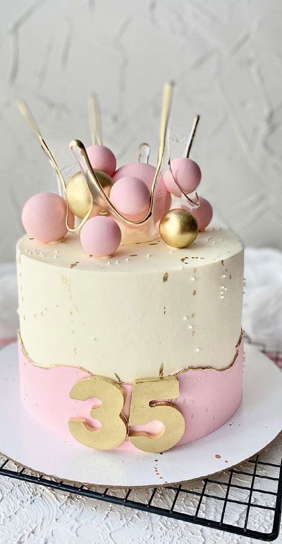 a cake with pink and white frosting on top is decorated with gold spoons