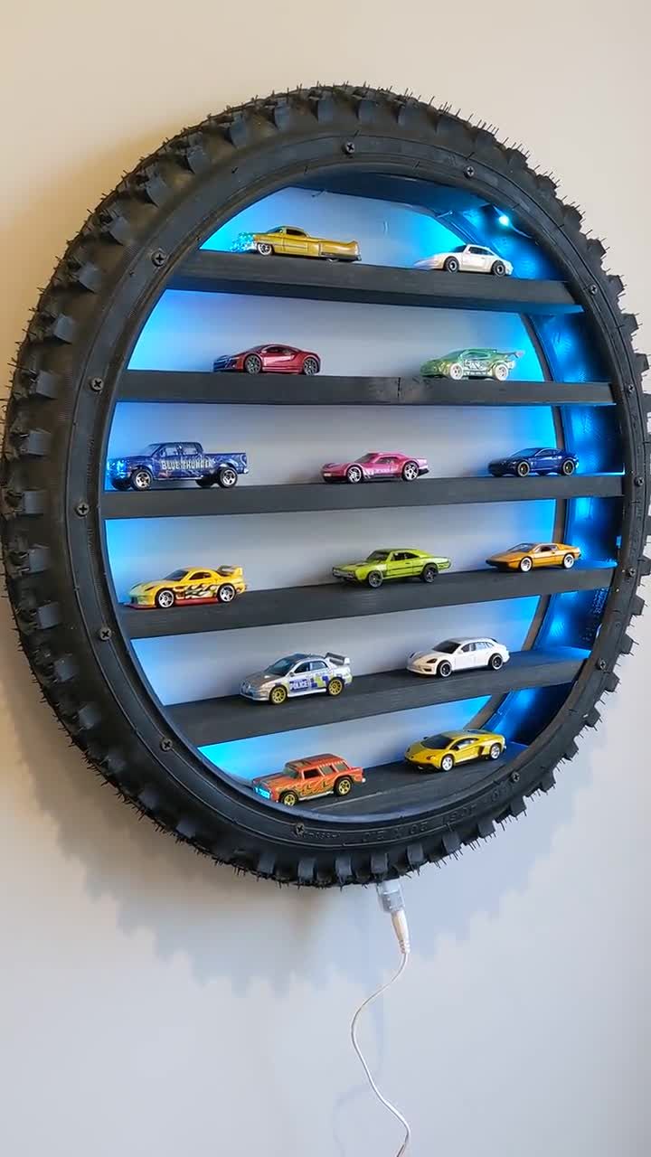 a wall mounted toy car display in a circle with blue lights on the rims