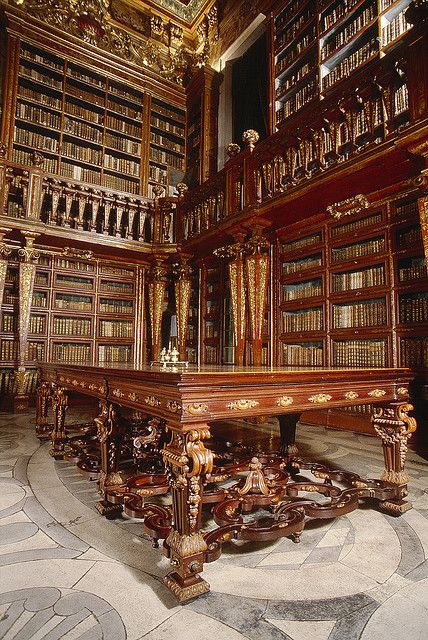 an ornate library with many bookshelves and tables