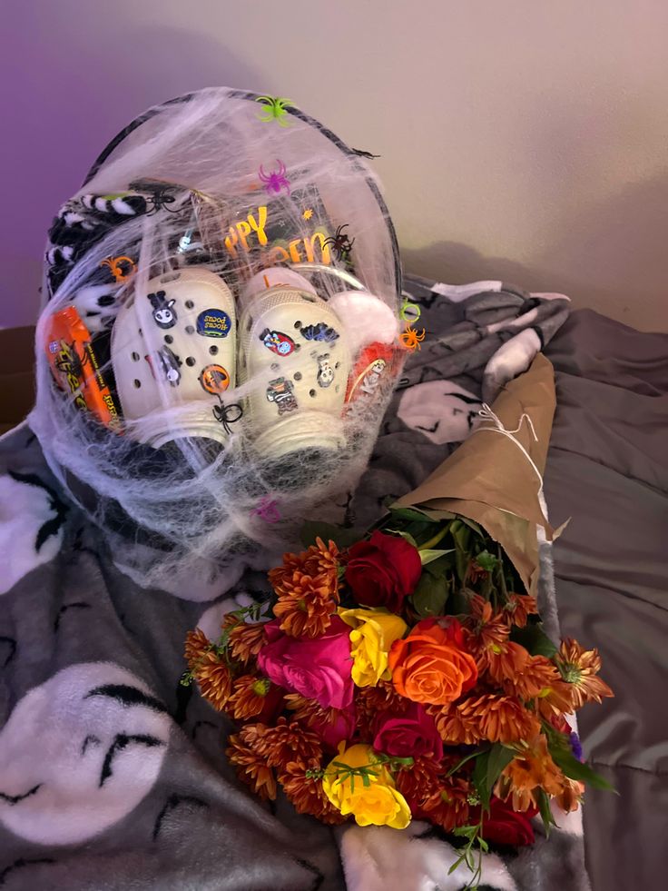 a bouquet of flowers and two white masks on a bed with a gray blanket that says happy halloween