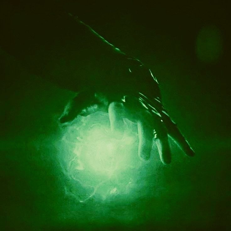 a person's hand is glowing green in the dark