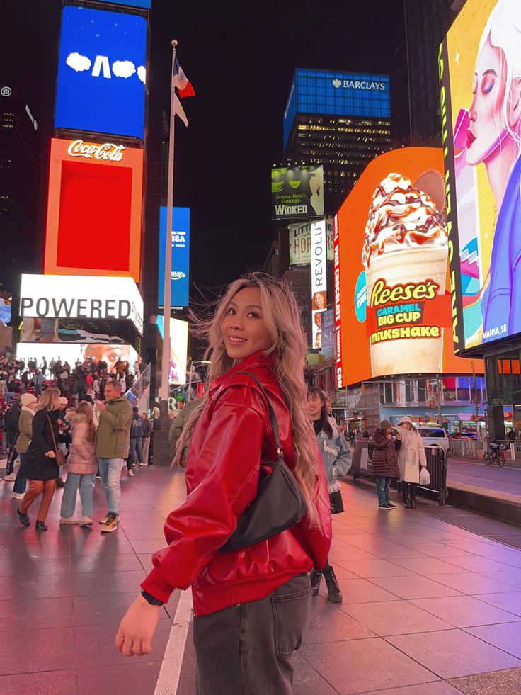 a woman standing in the middle of a busy city street at night with neon signs