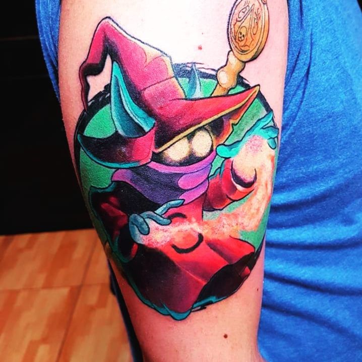 a man with a colorful tattoo on his arm wearing a hat and holding a spoon