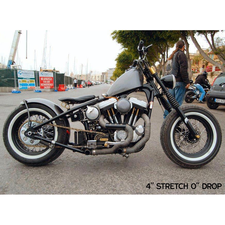 a black motorcycle parked on the street next to other cars and people standing around it