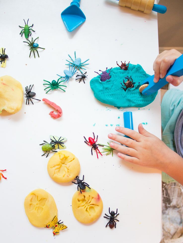 a young boy is playing with fake bugs and spider cookies on a white table top