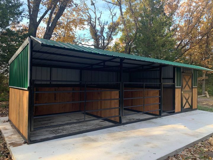 two horse stalls are shown in the middle of a wooded area with trees around them