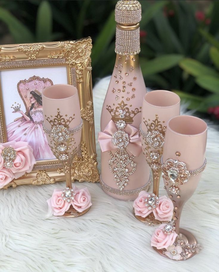 there is a pink vase and two wine glasses next to a picture frame on a white furnishing