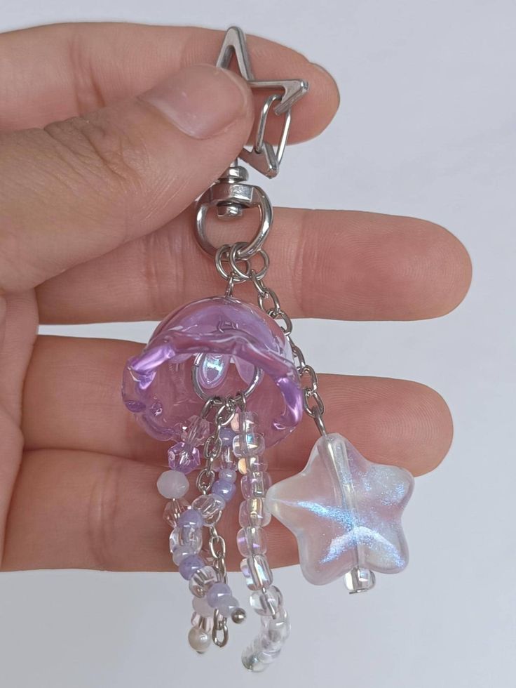 a hand holding a keychain with an octopus and starfish charm on it