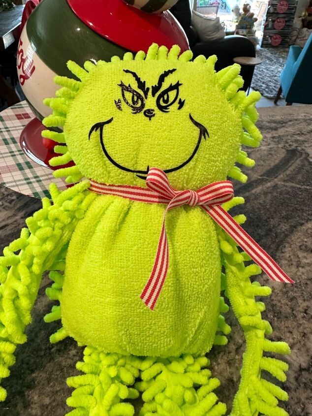 a green stuffed animal sitting on top of a counter next to a red and white object