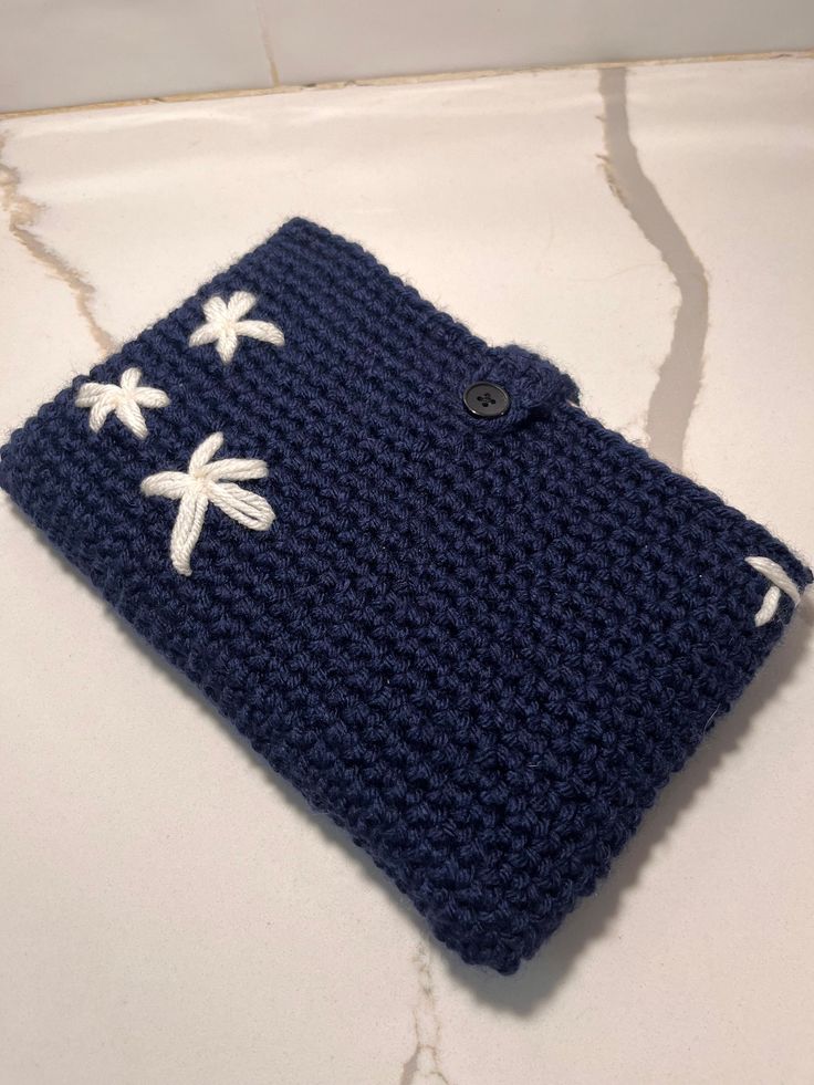 a blue crocheted square with white flowers on it and a button in the middle