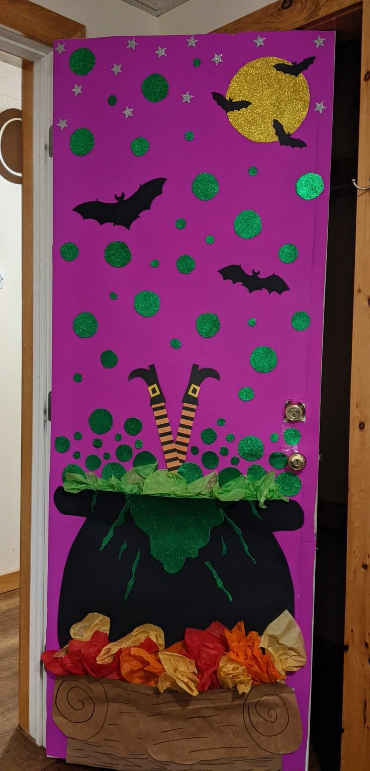 a door decorated to look like a witch's caulder with pumpkins