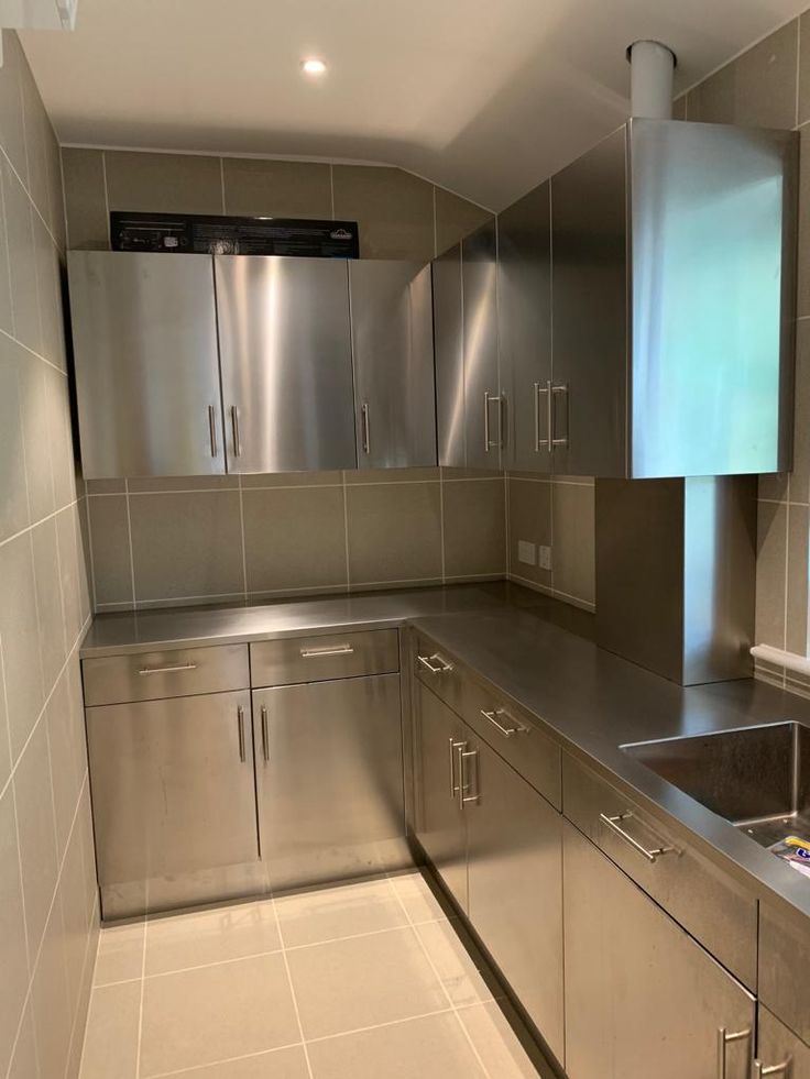 an empty kitchen with stainless steel appliances and tile flooring is pictured in this image