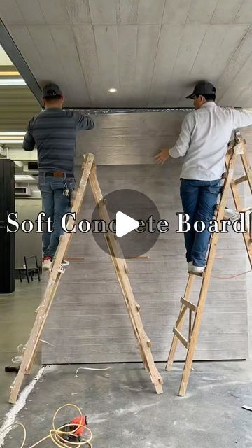 two men are working on the ceiling in a room that is being built with wooden ladders