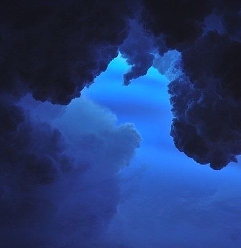 the sky is dark and blue with clouds in it, as seen through an opening