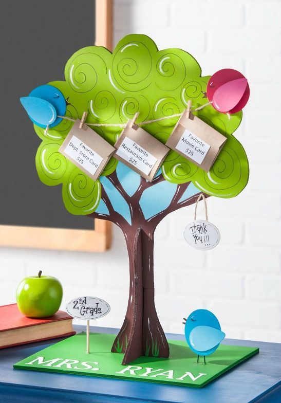 an apple tree with three cards attached to it and two books on the table next to it