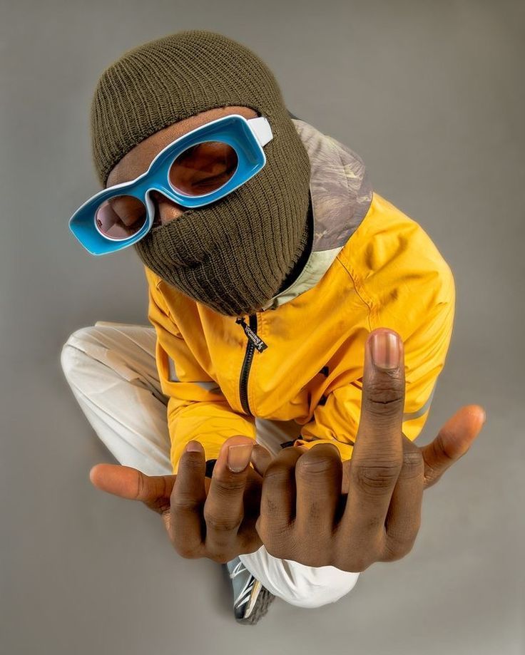 a person wearing a yellow jacket and blue sunglasses making the peace sign with their fingers