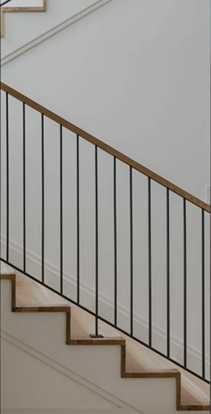 a cat sitting on top of a wooden stair case next to a bannister