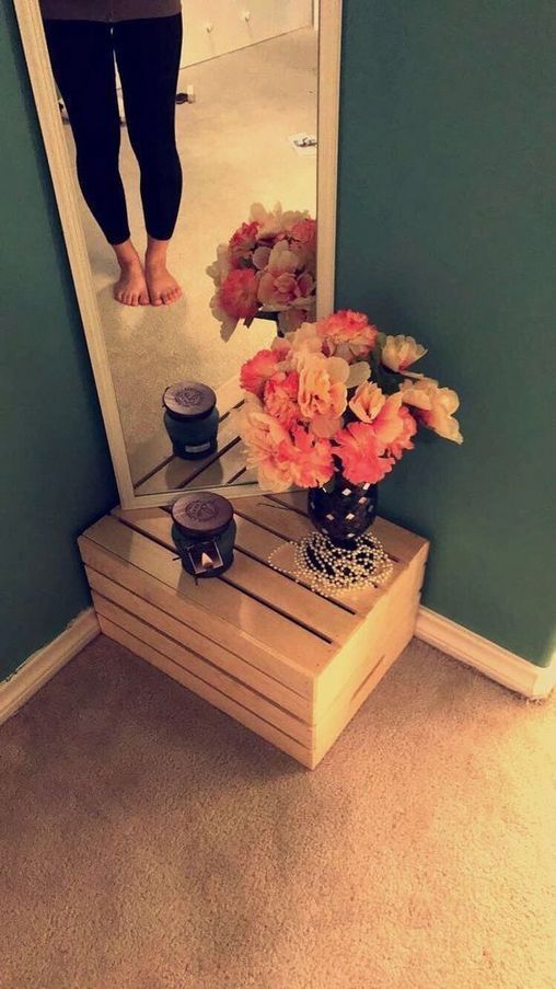 a vase with flowers sitting on top of a wooden table in front of a mirror